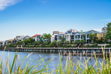 Obraz premium Wide panoramic view of Emerald Lakes residences across the lake, on a blue sky background during a beautiful sunset. Gold Coast, Australia.