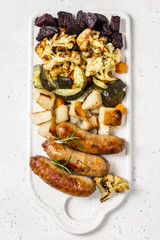 Grilled sausages with baked zucchini, potatoes, beets and cauliflower. Top view, space for text.