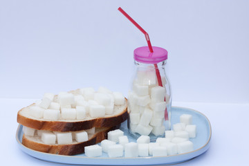 Sandwich with sugar and bottle full of sugar cubes. Too much sugar and unhealthy food concept.