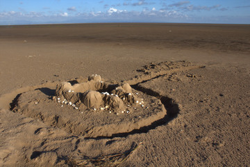 A weathered sand castle on an empty beach