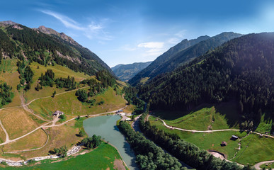 Beautiful aerial wide view on mountain city. Summer sunny day, river lake and buildings. Entrance to the wildpark at the Grossglockner High Alpine Road in Ferleiten, Austria.