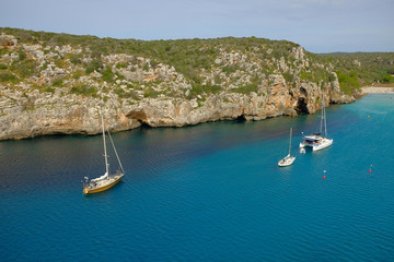 View on on the beach Cala en Porter with white boats, Menorca.