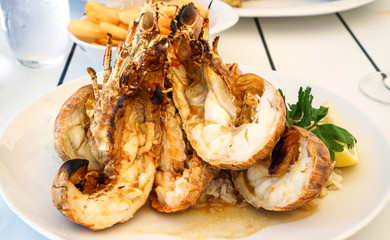 Delicious freshly cooked king prawns on a white plate, served on a white wooden table at seafood restaurant. 