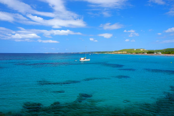 View on the beach Son Bou and white boat on the Balearic Island Menorca, Spain.