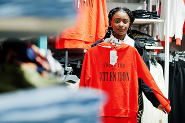 Afican american women in tracksuits shopping at sportswear mall against shelves with sweatshirt. Sport store theme.