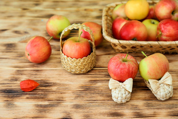 Red apples lie in a wicker plate on a wooden table. Wicker shoes and apples in a basket. Healthy...
