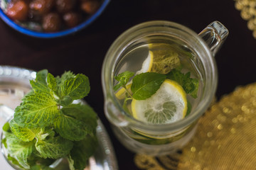 homemade lemonade in a jug with lime, mint and lemon on a colored background