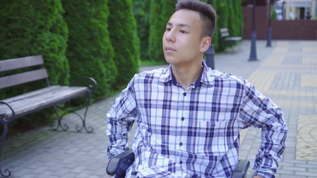 Portrait young asian man disabled in wheelchair rides in park