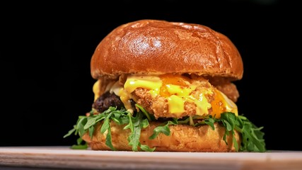 Craft burger is cooking on black background. Consist: sauce, arugula, tomato, red onion rings fries, cucumber, cheese, air bun and marble meat beef.