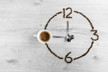 Coffee beans folded in the form of a clock. Instead of the number 9, a cup of coffee, which means...