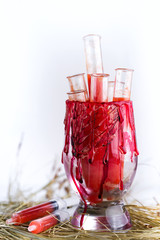 Halloween bloody glass with test tubes of tomato juice. Party drinks on white background