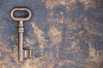 Antique rusty ornate key on grunge metal background, escape room concept