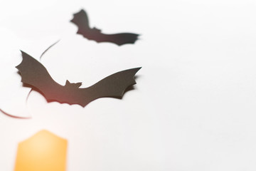 Halloween decorations with paper bats, candles and ghosts on white background. Halloween and decoration concept. Lens flare effect. Flat lay, top view, copy space