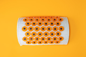 Acupuncture massager-applicator in the form of a roller for the neck with magnets for intense exposure. The concept of health care, cervical disease, osteochandrosis. Top view, orange background.