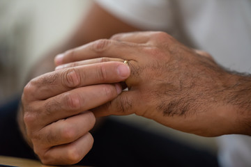 sad man takes off his wedding band from his hand, close up