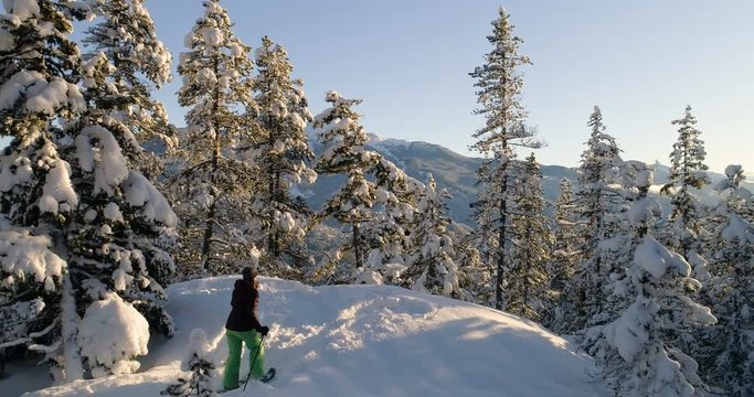 Woman Snowshoeing Through Snow covered at trees at sunset