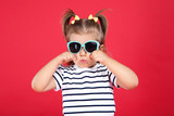 Cute little girl in sunglasses on red background