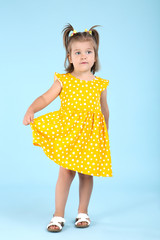 Cute little girl in yellow dress on blue background