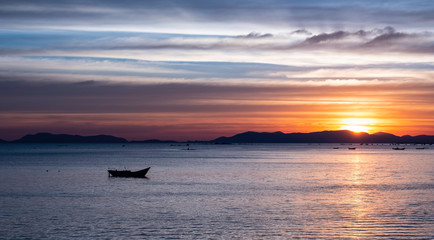 fishing boat and beautiful sky color  in calm bay sunrise of amazing intensity  changing weather ..Stunning sunset over small fishing boat in foreground.