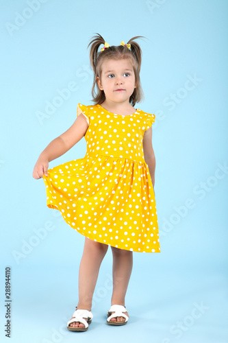 Cute little girl in yellow dress on blue background