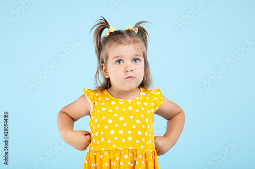 Cute little girl in yellow dress on blue background