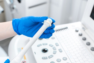 gynecologist puts a condom on the ultrasound sensor to examine the internal organs of the patient's pelvis