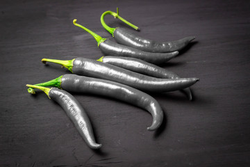 Naklejka premium Studio shot of group of black chili peppers isolated on a black background.