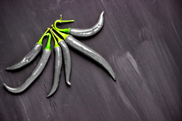 Studio shot of group of black chili peppers isolated on a black background.
