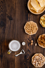 Beer glass with bottle cap and snack on wood background. top view. copy space