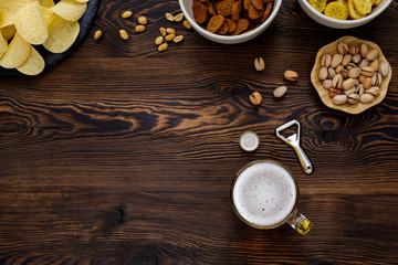Beer glass with bottle cap and snack on wood background. top view. copy space