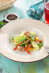 Healthy Grilled Chicken Salad with fresh vegetables and glass of red drink on blue wooden table