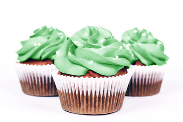 Three delicious cupcakes with icing in trendy neo mint color on white background. Close-up.