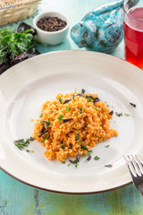 Bulgur with basil and squash and glass of berry drink on blue wooden table