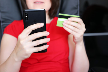 Woman holding credit card and smartphone in hands. Concept of online shopping and payment by mobile phone