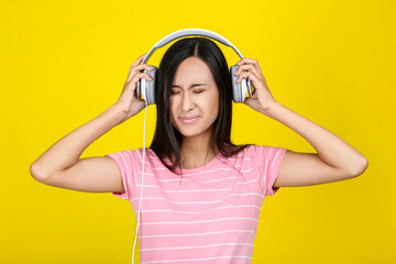 Beautiful woman with headphones on yellow background