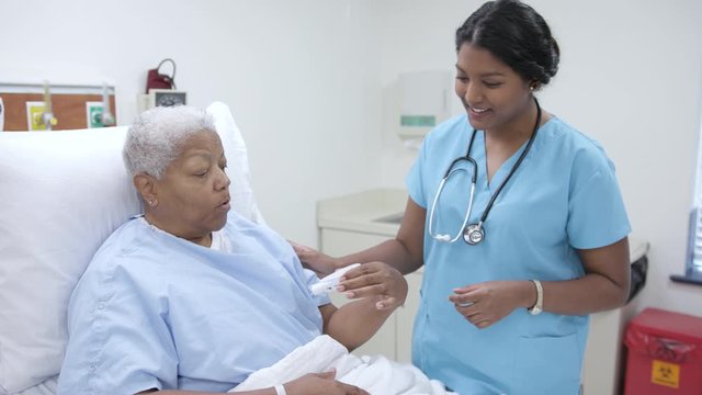 Nurse helps female patient with flow meter in hospital patient room