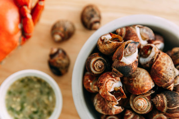 Top view of Grilled Laevistrombus Canarium in shells served with Thai spicy seafood sauce on wooden plate.