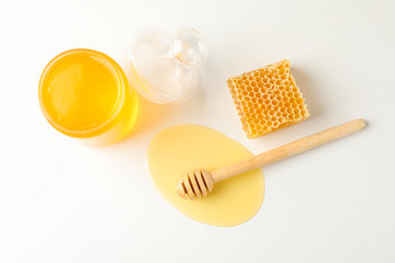 Jar with honey, dipper and honeycomb on white background, copy space