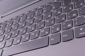 A silver-gray laptop with a modern keyboard connected to the Internet and a computer network lies on an orange desktop in an office