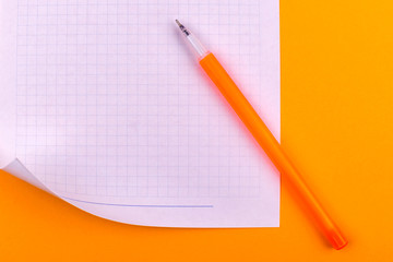 A white sheet of paper for drawings, texts, letters and notes, next to a yellow pen lies on an orange background