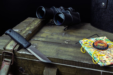 Knife, binoculars and a map of the area. Search route and road.
