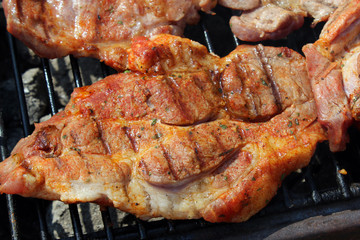 Pork neck getting grilled on open fire