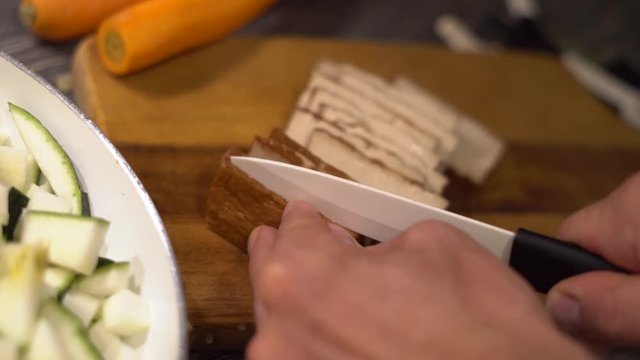 Tofu wird in Scheiben geschnitten auf einem Holzbrett