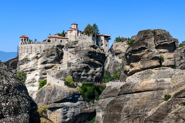 Fototapeta na wymiar Rock formations of Meteora mountains and the monastery in Greece with blue sky and green forest