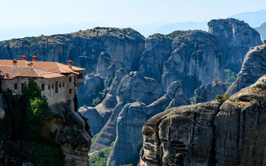 Fototapeta premium Rock formations of Meteora mountains and the monastery in Greece with blue sky and green forest