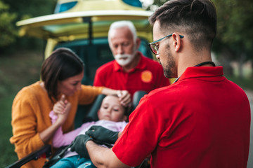 Scared mother standing with doctors and her injured daughter.