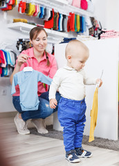 kid who is posing when his mother choosing clothes