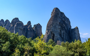 Rock formations of Meteora mountains and the monastery in Greece with blue sky and green forest