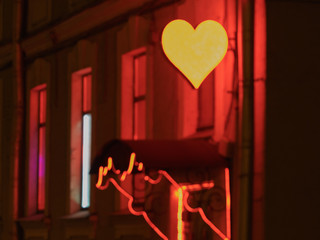 Photography of the illuminated heart on the city street. Romantic concepts of modern lifestyles. Red-light in night..