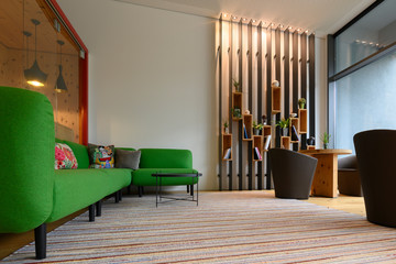 interior design with green sofa chairs and black vertical metal flower bookshelf